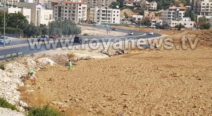 عمال وطن يقومون بإحراق النفايات على قارعة الطريق 
