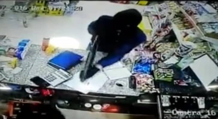 أحد أفراد العصابة يشهر سلاحه مهددا صاحب المتجر