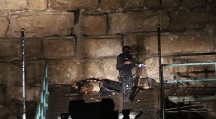 أحد عناصر الأمن بالقرب من جثث المسلحين في قلعة الكرك 