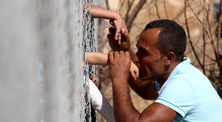 السوري عمار حمشو يقبل يد أبنائه عبر سياج في قبرص