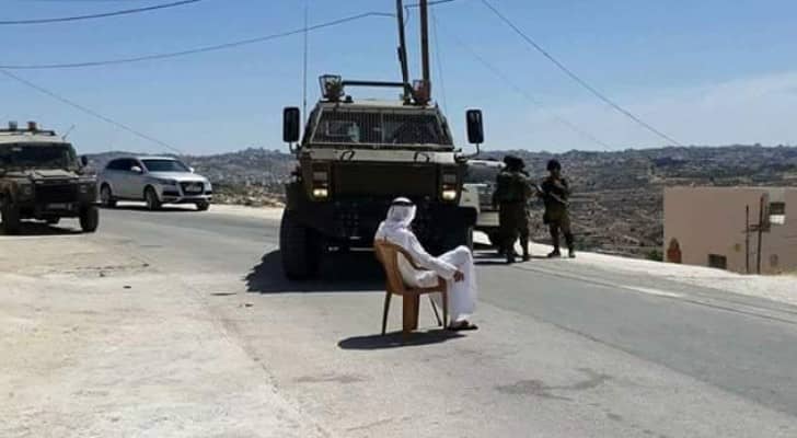 مسن فلسطيني يجلس أمام الآلية العسكرية 