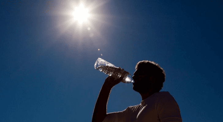 شخص يشرب الماء وسط أجواء حارة