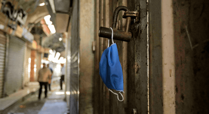 كمامة معلقة على باب أحد المحلات التجارية في قطاع غزة