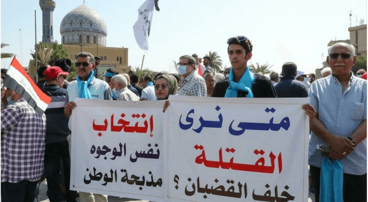 عراقيون يرفعون لافتات أثناء تجمعهم في ساحة الفردوس وسط بغداد