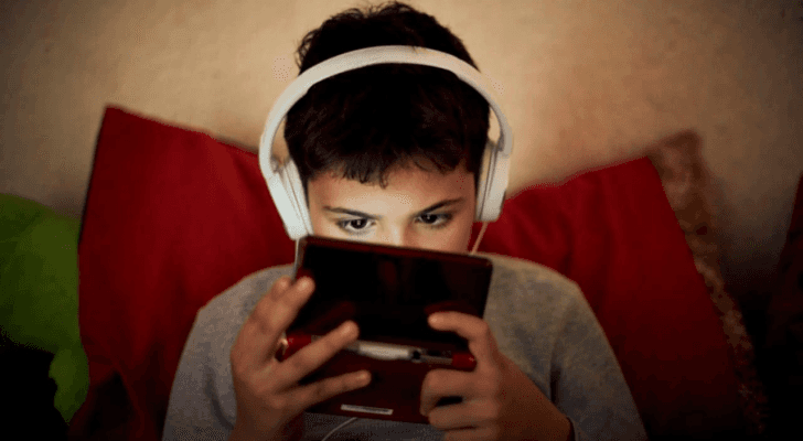 طفل يلعب على جهاز إلكتروني