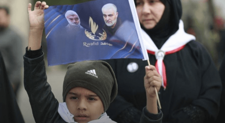 طفل عراقي يرفع صورة لسليماني والمهندس في بغداد (أ ف ب)