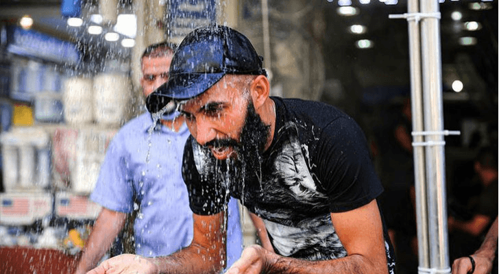شاب يغتسل بالماء نتيجة ارتفاع درجات الحرارة