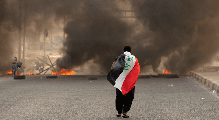 شخص يحمل العلم العراقي أثناء الاضطرابات التي شهدتها البلاد