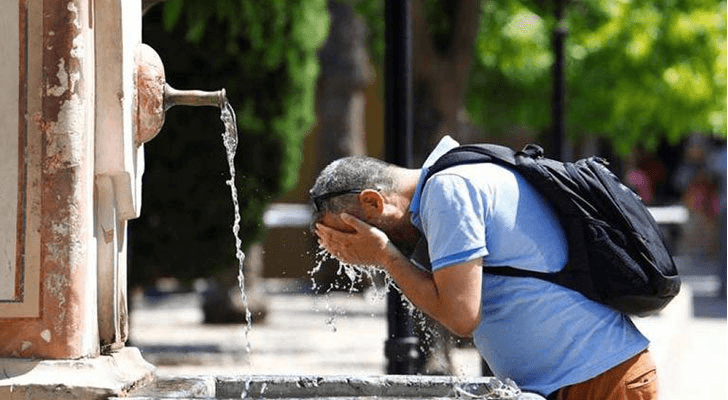 رجل يسكب الماء على وجهه من شدة حرارة الطقس
