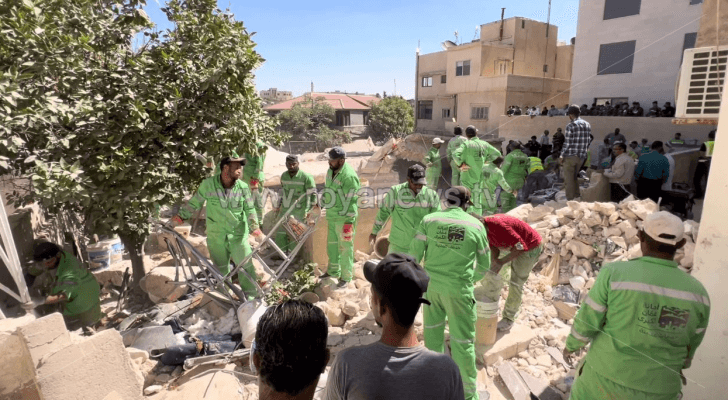 كوادر أمانة عمان أثناء إزالتهم للركام إلى جانب كوادر الدفاع المدني