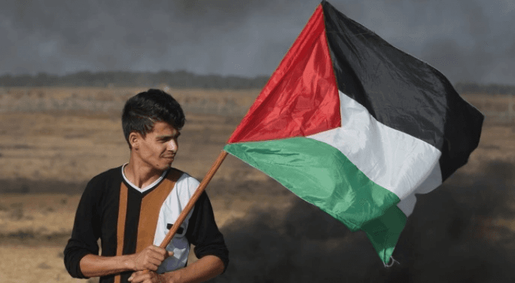 شاب فلسطيني يرفع العلم الفلسطيني