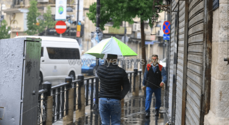 شخص يحمل مظلة تحت المطر في وسط البلد بالعاصمة عمان