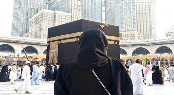صورة تعبيرية لمعتمرة تقف أمام الكعبة المشرفة