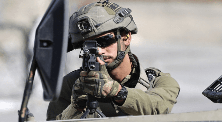 جندي في جيش الاحتلال يصوب بندقيته نحو فلسطينيين
