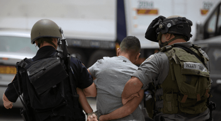 صورة أرشيفية لعنصرين في قوات الاحتلال يعتقلان شابا فلسطينيا