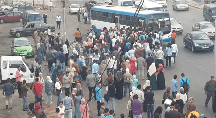 مواطنون ينتظرون حافلة في موقف حافلات بالعاصمة عمان - أرشيفية