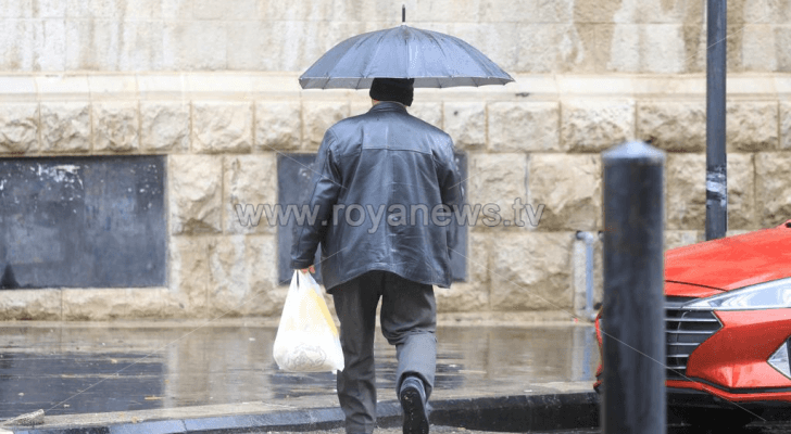 شخص يحمل مظلة في أحد شواع العاصمة عمان