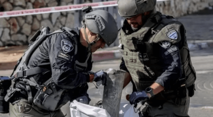 جنديان "إسرائيليان" يضعان شظية صاروخ سقط في شمال فلسطين المحتلة بعد أن انطلق من لبنان