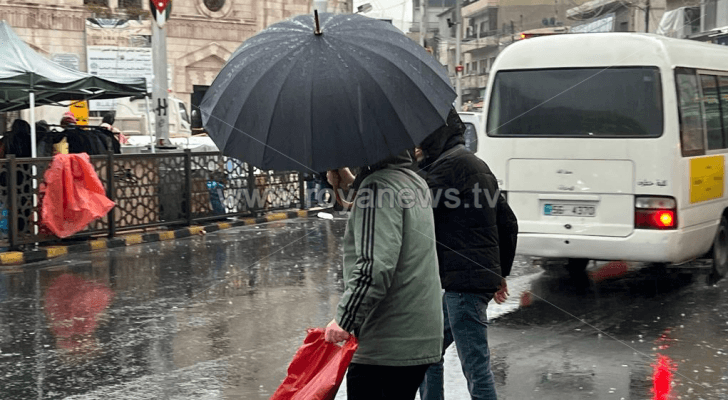 شخص يحمل مظلة في أحد شواع العاصمة عمان