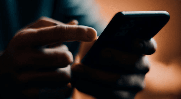 صورة تعبيرية لشخص يحمل جهازا خلويا عبر تقنية الذكاء الاصطناعي