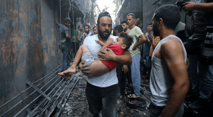 فلسطيني يحمل طفله بعد قصف منزله في قطاع غزة