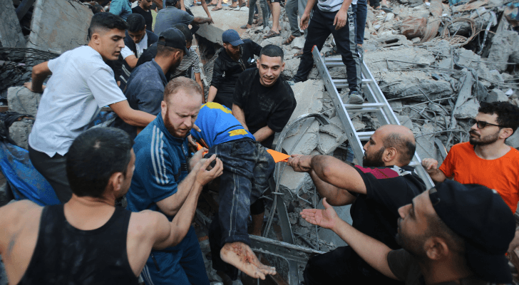 فلسطينيون ينتشلون شهيدا من تحت أنقاض الركام جراء قصف الاحتلال الإسرائيلي