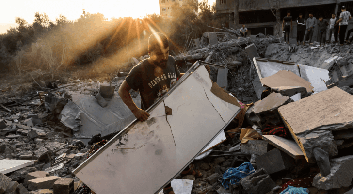 فلسطيني يحمل آثار دمار قصف الاحتلال الإسرائيلي على قطاع غزة