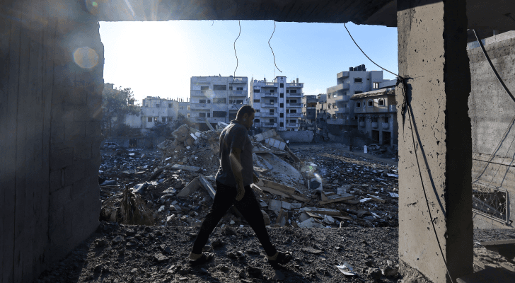 رجل فلسطيني يمشي وسط أنقاض مبنى تم تدميره في ضربة جوية في مخيم رفح جنوب قطاع غزة