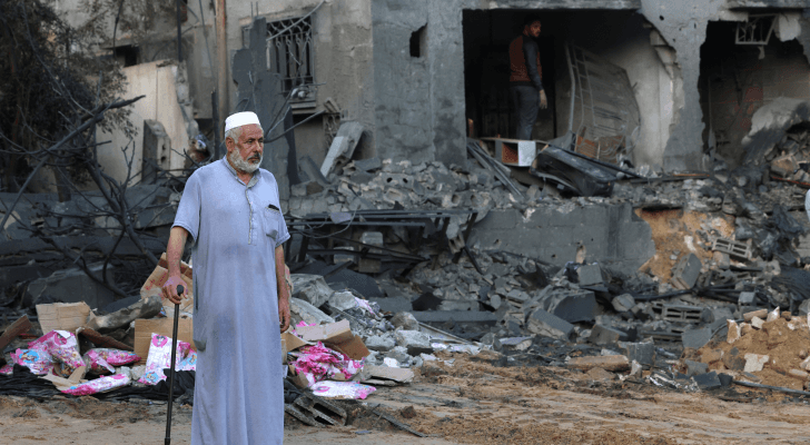 مسن فلسطيني يقف بالقرب من منزل تعرض للقصف