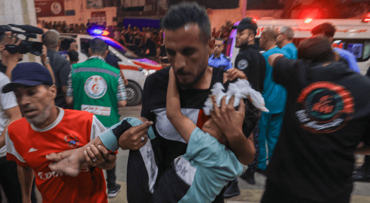 فلسطيني يحمل طفله المصاب من جراء قصف الاحتلال مستشفى المعمداني في غزة