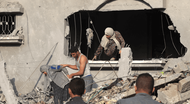 فلسطينيون يحاولون الخروج من بين ركام منزل مدمر في قطاع غزة
