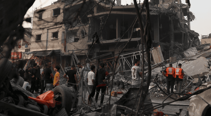 فلسطينيون فوق أنقاض مبنى تم تدميره في ضربة جوية في قطاع غزة