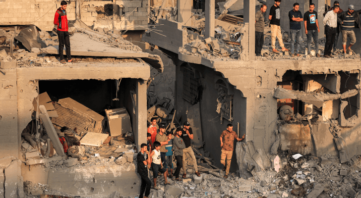 فلسطينيون يقفون على أنقاض دمار خلفه قصف الاحتلال الإسرائيلي في قطاع غزة