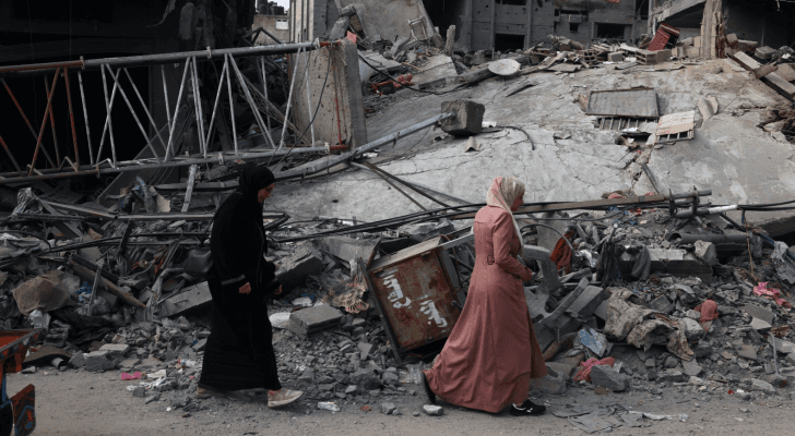 فلسطينيتان تمشيان أمام دمار خلفه قصف الاحتلال الإسرائيلي