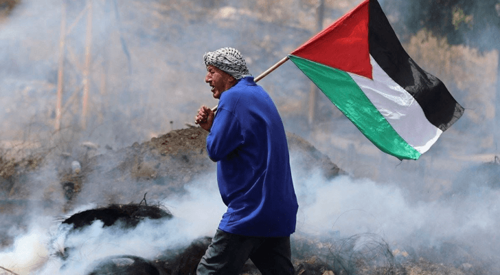 فلسطيني يحمل علم فلسطيني ويسير بين الركام "تعبيرية"