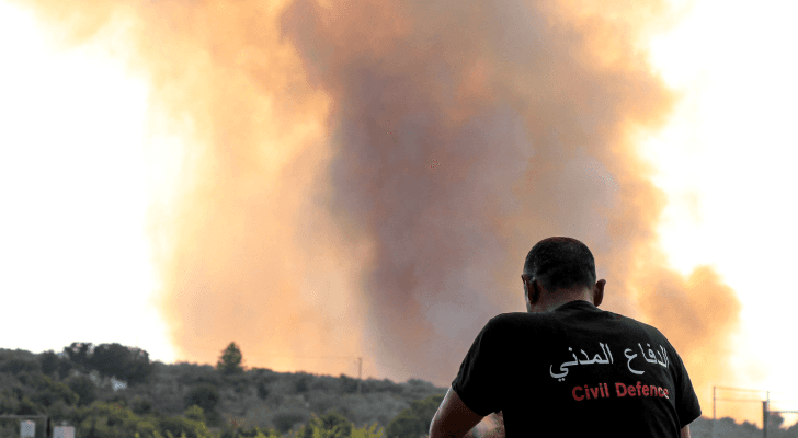 أحد عناصر الدفاع المدني في لبنان بينما يتصاعد عمود من الدخان خلال حريق اشتعل بعد إطلاق قذيفة من الاحتلال