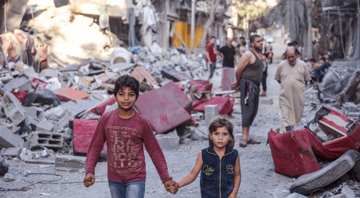 فلسطينيون يسيرون في شارع مدمر في أعقاب غارات الاحتلال