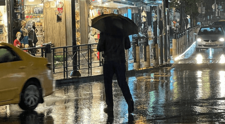 شخص يحمل مظلة في أحد شورع العاصمة عمان