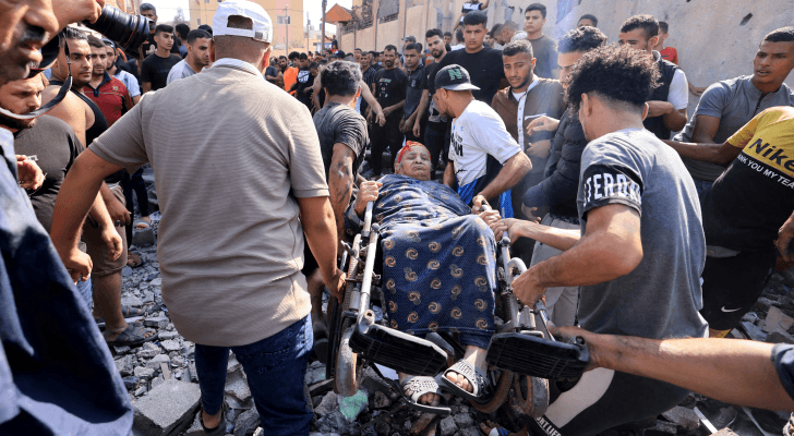فلسطينيون ينقلون سيدة أصيبت بقصف الاحتلال الإسرائيلي على قطاع غزة