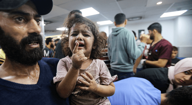 فلسطيني يحمل طفلة مصابة بقصف الاحتلال