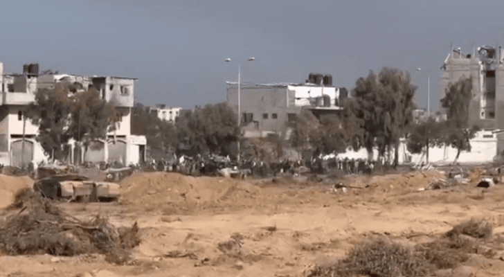 صورة ملتقطة من مقطع الفيديو الذي نشره الاحتلال الإسرائيلي تظهر دبابة مقابل توافد فلسطينيين نازحين بالرايات البيضاء