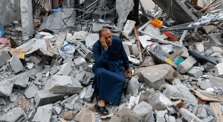 فلسطيني يجلس فوق الركام في غزة