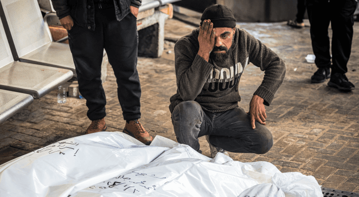 فلسطيني يجلس بجانب جثمان أحد أقاربه الذي ارتقى في قطاع غزة