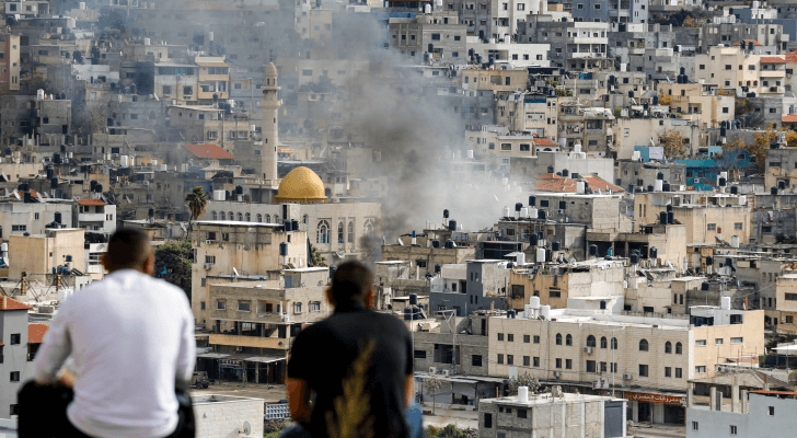 فلسطينيان يراقبان تصاعد الدخان خلال مواجهات اندلعت بين مقاومين وقوات الاحتلال بمخيم نور شمس في طولكرم