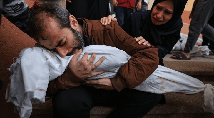 فلسطيني يحمل طفلة استشهدت جراء قصف الاحتلال الإسرائيلي