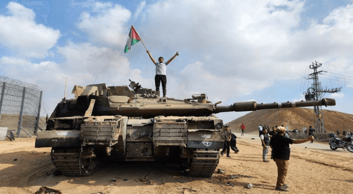 فلسطيني يرفع علم بلاده فوق دبابة مع بدء طوفان الأقصى