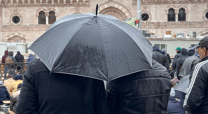شخص يحمل مظلة في أحد شورع العاصمة عمان