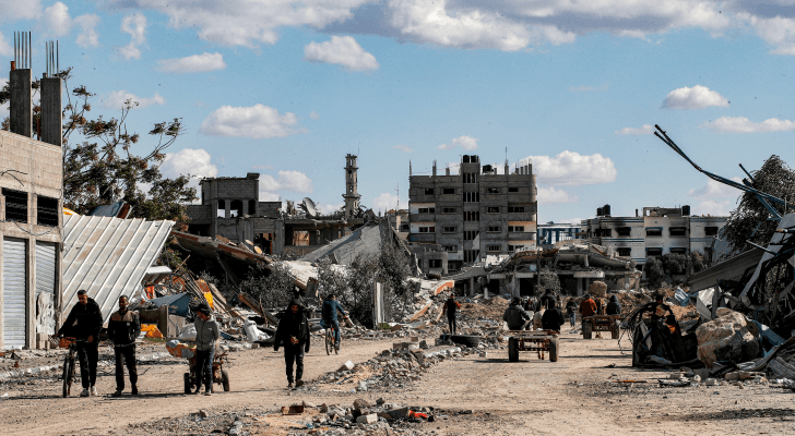 فلسطينيون وسط المباني المدمرة في مخيم المغازي للاجئين الفلسطينيين