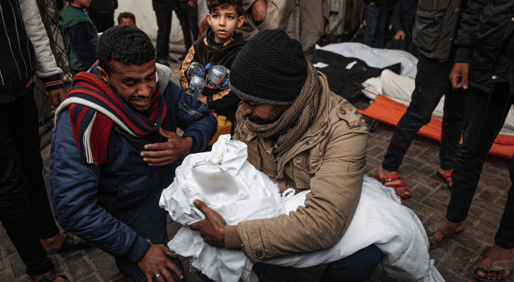 فلسطيني يحمل صغيره الشهيد في غزة