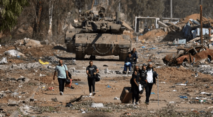فلسطينيون يسيرون في شارع مدمر في أعقاب غارات الاحتلال